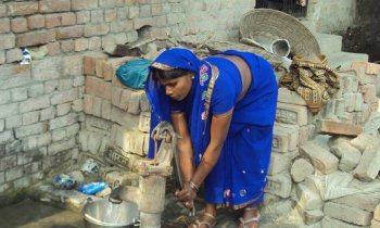 Frau sch�pft Wasser mit Handpumpe in Tirmasahun, Indien